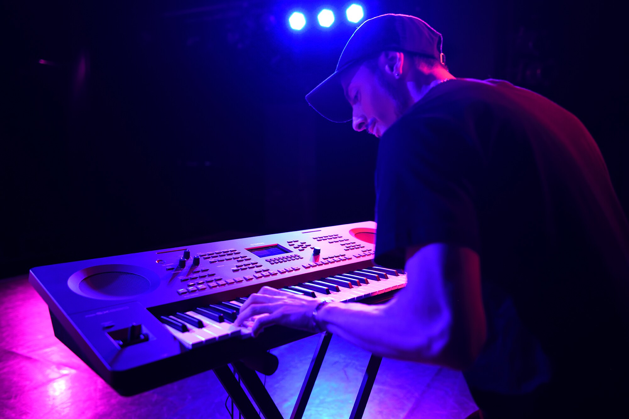Eine Person spielt auf einer Yamaha Arranger-Workstation auf einem Ständer unter Bühnenbeleuchtung