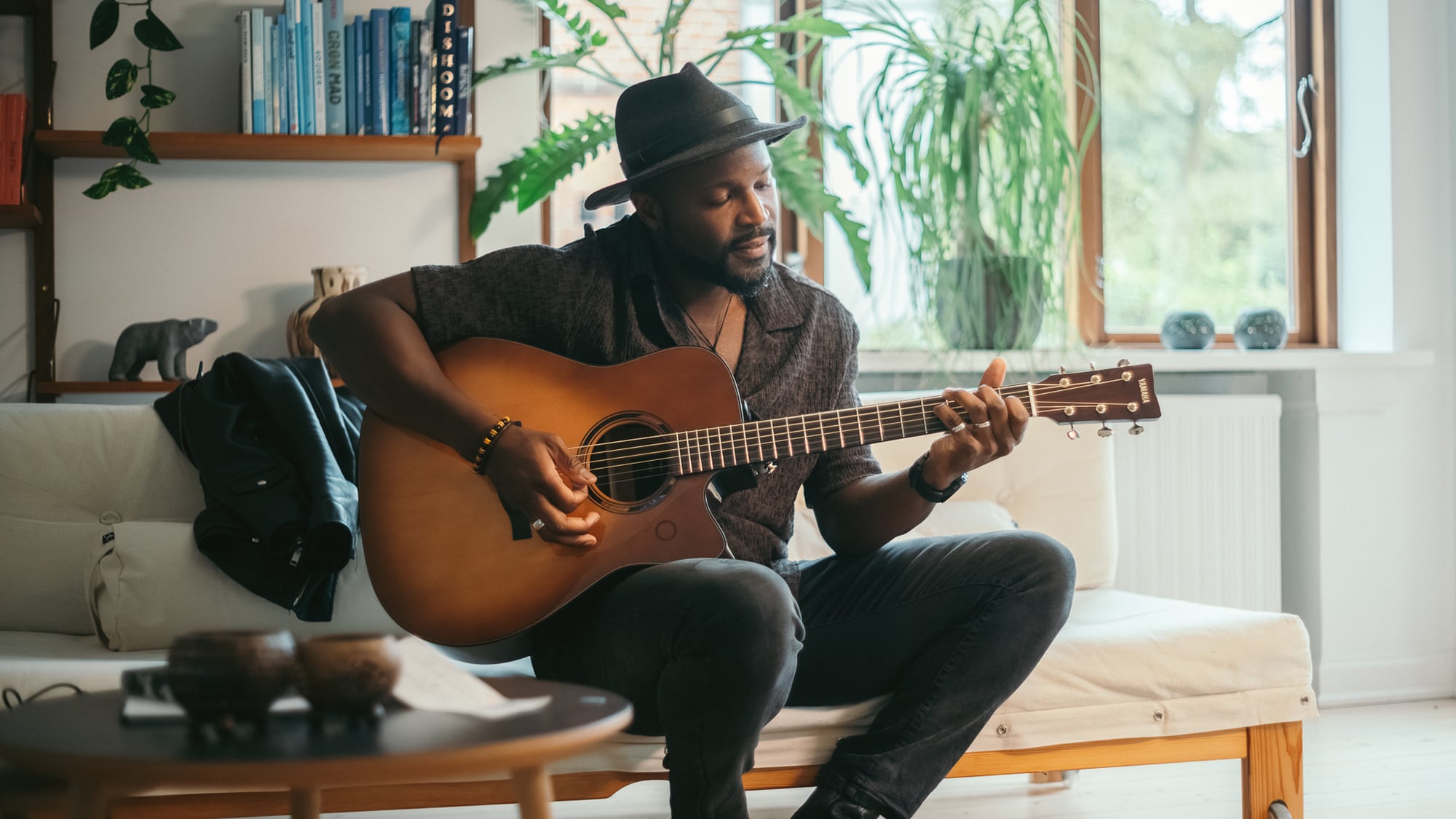 Man sitting indoors playing the TAG3 C acoustic guitar.