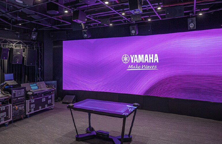 Bangkok training facility with Yamaha display wall, stage area, and professional audio equipment.
