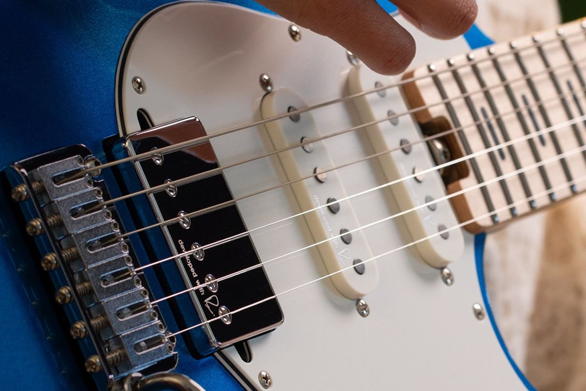 Closeup of Reflectone pickups on a Sparkle Blue Pacifica with a person strumming.